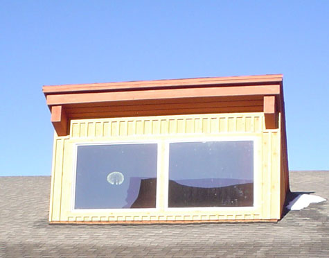 A close up of the dormer with board and batten cedar siding.